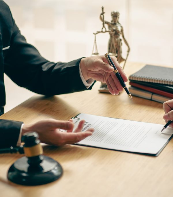 Business people or lawyers discussing contracts or business deals at a law firm. Justice advice service concept with hammer and goddess of justice beside, vertical image.