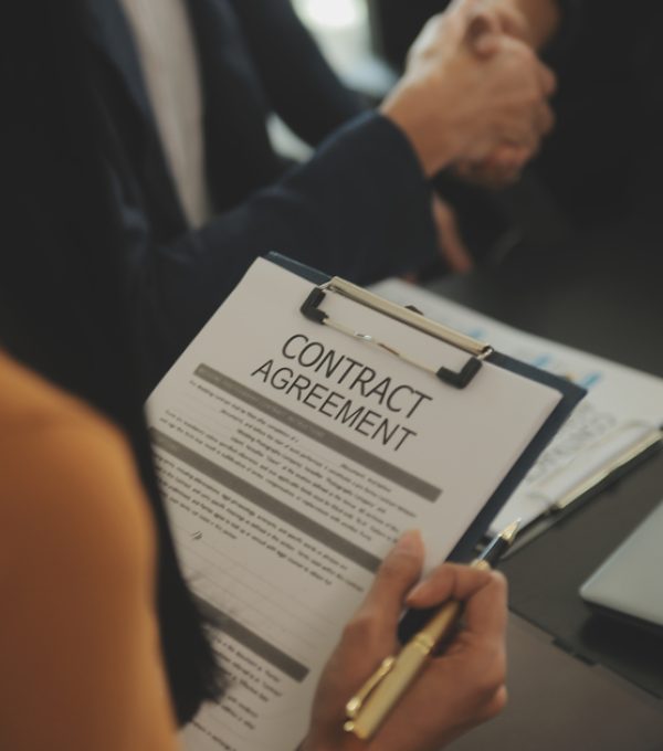 Justice and Law concept. Legal counsel presents to the client a signed contract with gavel and legal law or legal having team meeting at law firm in background